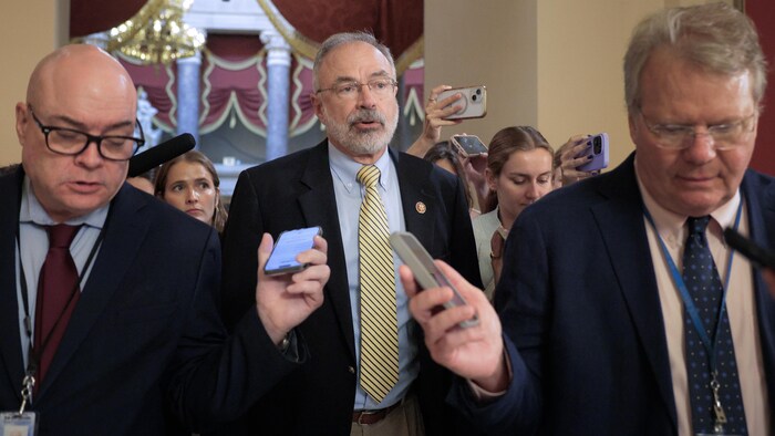 Un homme est entouré de journalistes.