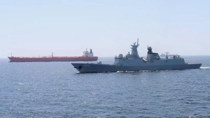 Un navire de guerre escorte un bateau.