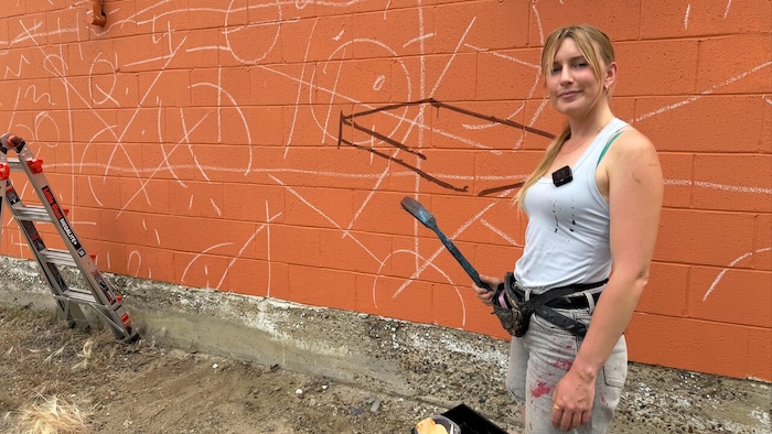 Megan Oldhues qui pose devant les prémises de sa fresque.