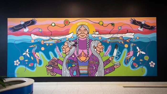 Fresque murale représentant des aînés autochtones au centre d’une île au soleil couchant. 