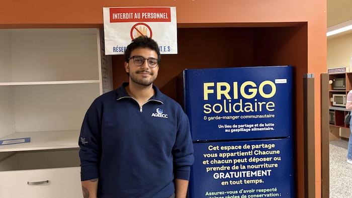 Hussein Chamouni pose devant le frigo solidaire. 