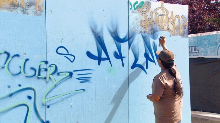 Un artiste fait des graffitis sur une peinture murale au Festival Fringe d'Edmonton 2022.