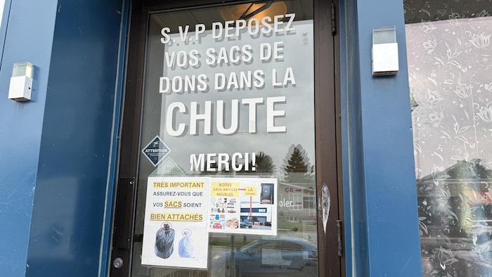 Porte d'entrée avec des affiches indiquant les marches à suivre pour déposer les dons.