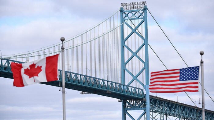 Des drapeaux canadien et américain flottent devant le pont Ambassador, qui permet de circuler de Windsor, en Ontario, à Détroit, dans le Michigan.