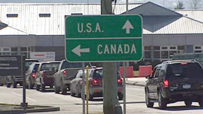Un panneau de signalisation avec une flèche menant vers les États-Unis et une autre vers le Canada.