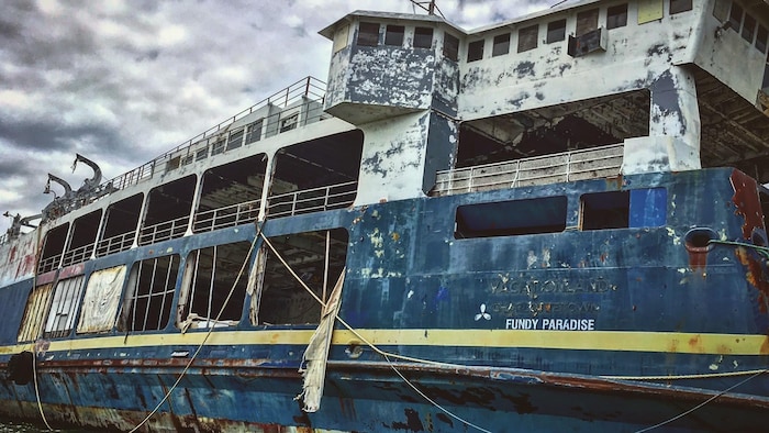 Un navire rouillé amarré dans un port.