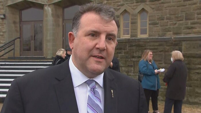 Un homme en entrevue devant l'église.