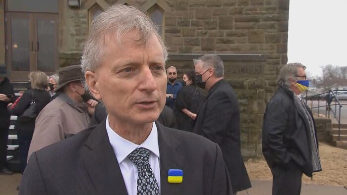 Un homme en entrevue devant l'église.