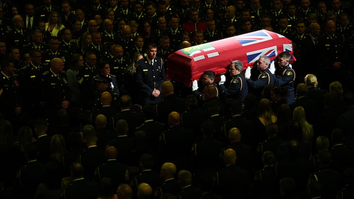Des policiers portent le cercueil d'Eric Mueller au milieu de l'assistance réunie au Centre Canadian Tire, à Ottawa.