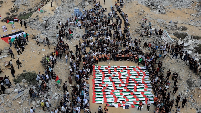 Des dizaines de personnes rassemblées autour de corps enveloppés du drapeau palestinien au milieu de décombres