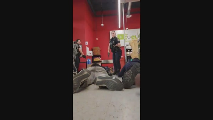 Une policière donne des indications aux clients couchés par terre.