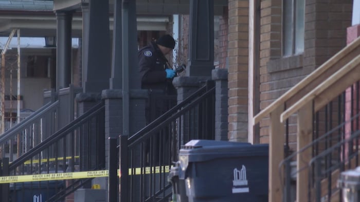 Un policier prend des photos sur le pas d’une porte de maison.