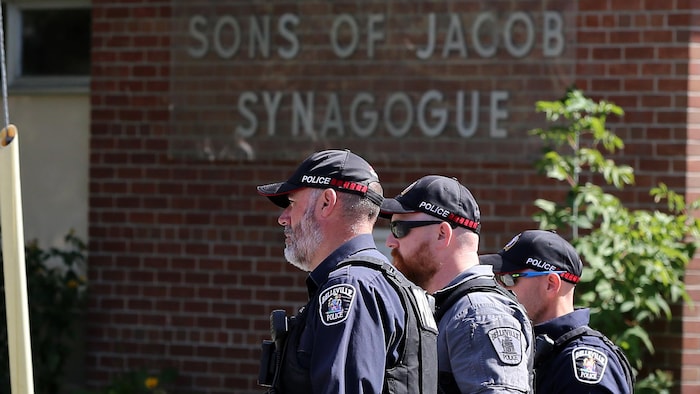 Des policiers passent devant la synagogue Son of Jacob à Belleville, en Ontario, le lundi 21 septembre 2026. Un homme armé d'un fusil de chasse aurait ouvert le feu sur un policier en poste devant une synagogue de Belleville, en Ontario, dimanche soir, déclenchant un échange de tirs qui a laissé l'homme et le policier grièvement blessés, a indiqué lundi l'organisme de surveillance de la police de l'Ontario.