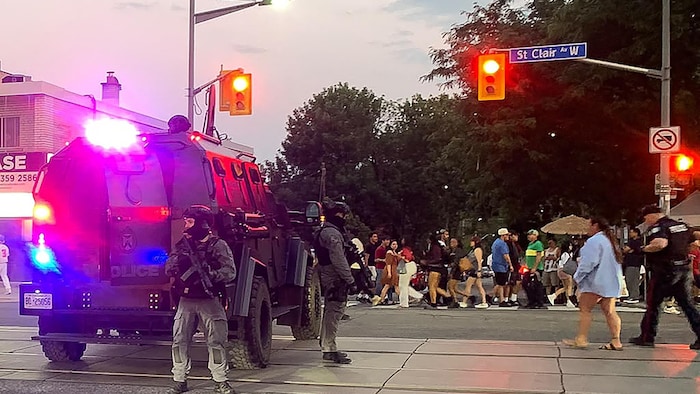 Des policiers armés sont debout au milieu de la rue.