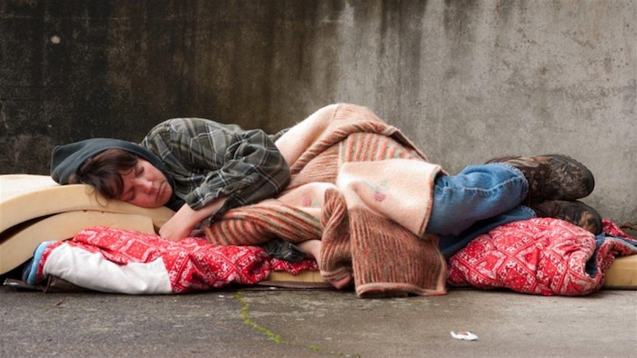 Une femme sans abri dort par terre.
