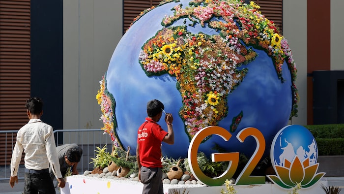 Le logo du G20 devant une planète Terre fleurie. 