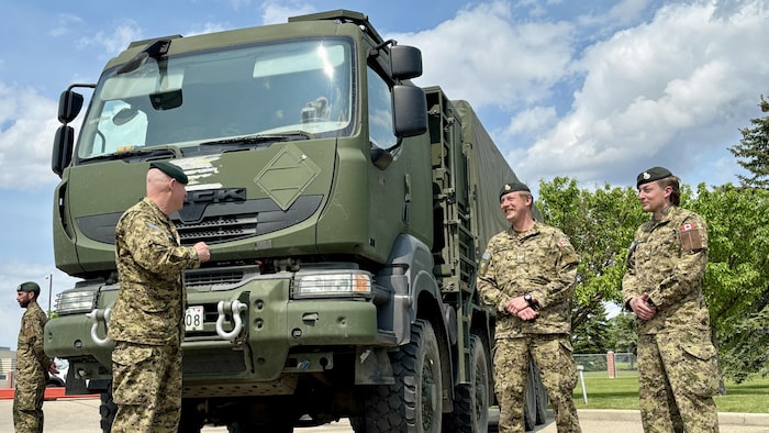 Des militaires en uniforme devant un camion de l'armée.