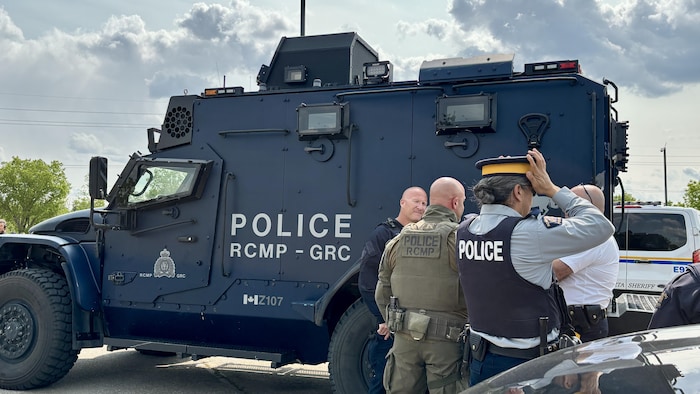 Des agents de la GRC devant un gros camion de la police.
