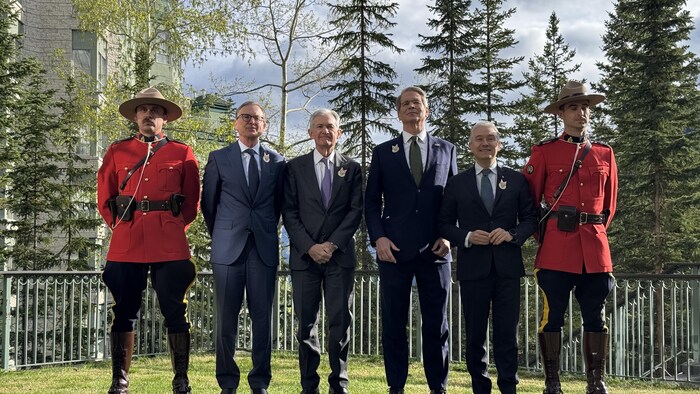 Photo des ministres des Finances du Canada et des États-Unis, accompagnés de deux agents de la GRC en uniforme traditionnel.
