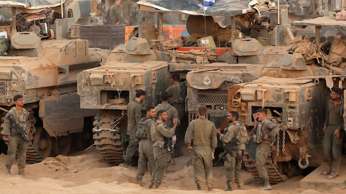 Des soldats de l'armée israélienne se rassemblent près de véhicules de combat d'infanterie.
