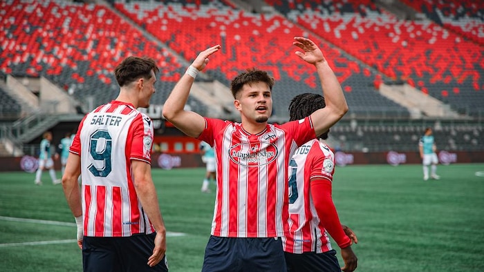 Un joueur de shot lève les bras au ciel vers la foule après avoir marqué un but.
