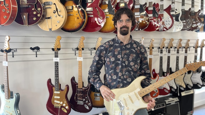 Un homme tient une guitare dans ses mains.
