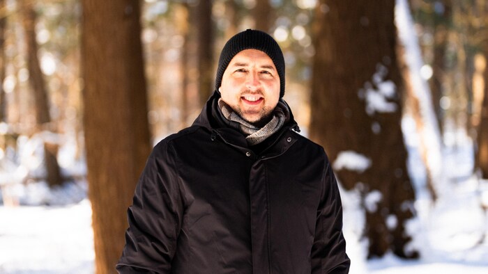 Gabriel Grenier pose dehors en hiver dans une forêt.
