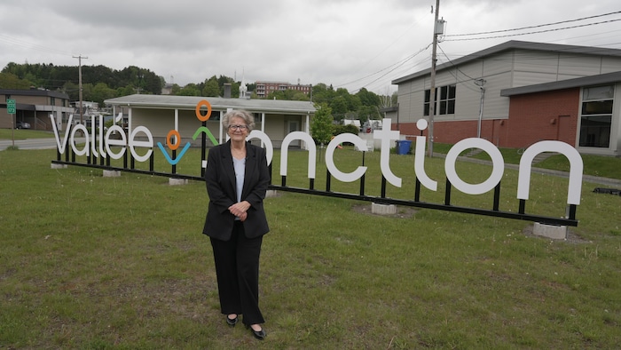 Une femme debout devant des lettres géantes indiquant : «Vallée-Jonction».