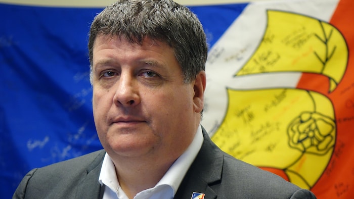 Gaël Corbineau se tient devant le drapeau francophone de Terre-Neuve-et-Labrador.