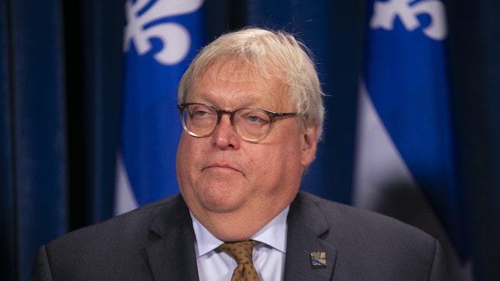 Le Dr Gaétan Barrette devant des drapeaux du Québec pendant un point de presse.