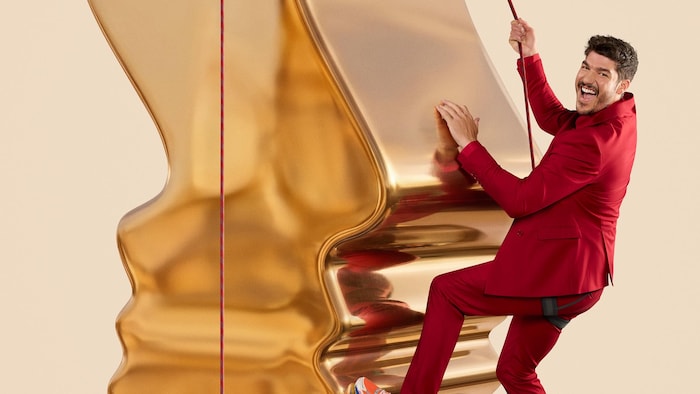 L'animateur grimpe sur une statuette géante des prix Gémeaux.