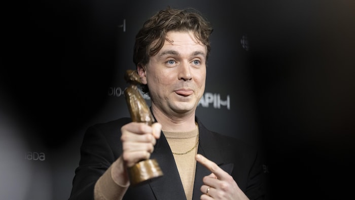 L'humoriste benignant la langue en pointant lad trophée.