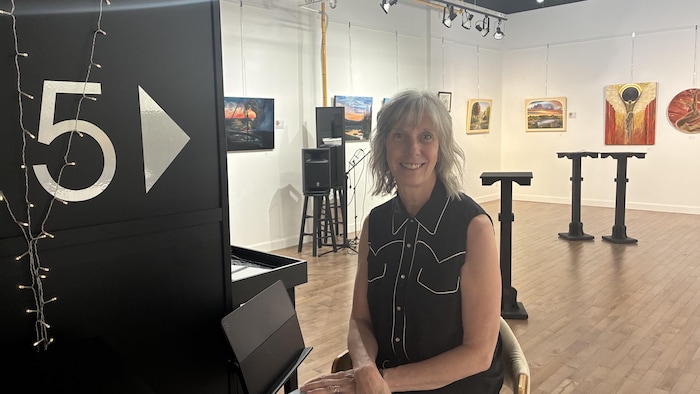 Une femme pose devant une salle d'exposition.