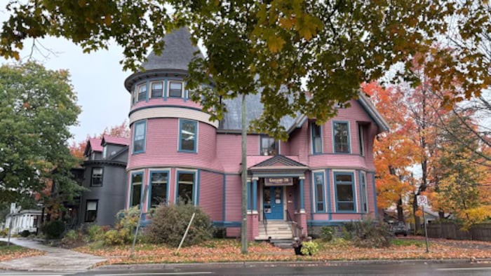 Une maison de style victorien de couleur rouge avec des tuiles de toit grises.