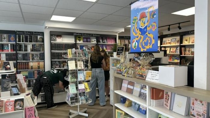 Dans une librairie, des personnes cherchent des livres sur les étagères  