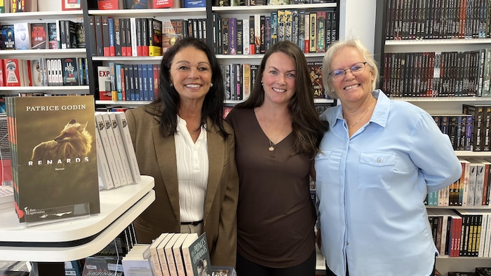 Marlène Côté, Noémi Lafleur-Allard et Mariane Côté posent bras dessus, bras dessous dans la Galerie du livre de Val-d'Or.