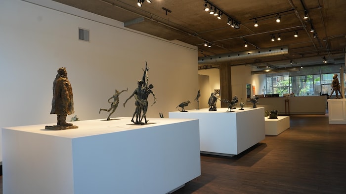 Des statues sont exposées dans une galerie. 