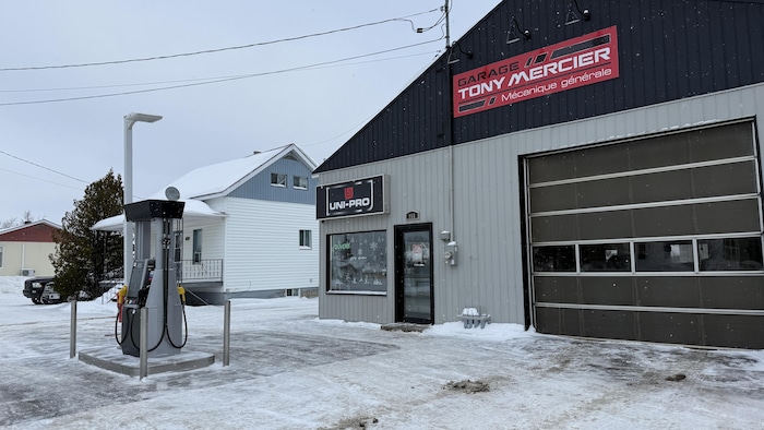 La façade d'un garage de mécanique générale avec une distributrice à essence à l'avant.