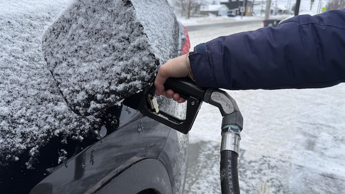 Une personne utilise un pistolet de remplissage pour mettre de l'essence dans sa voiture.