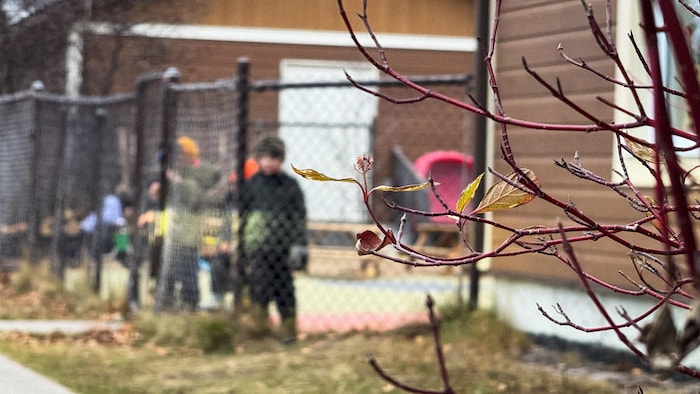 Des enfants derrière une grille de cour d'école.