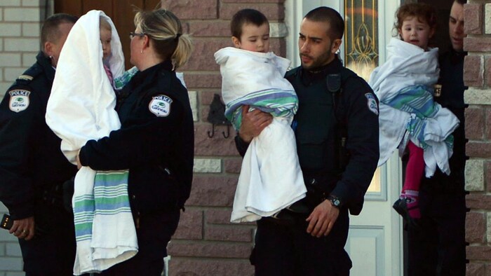 Des policiers avec un enfant dans les bras.
