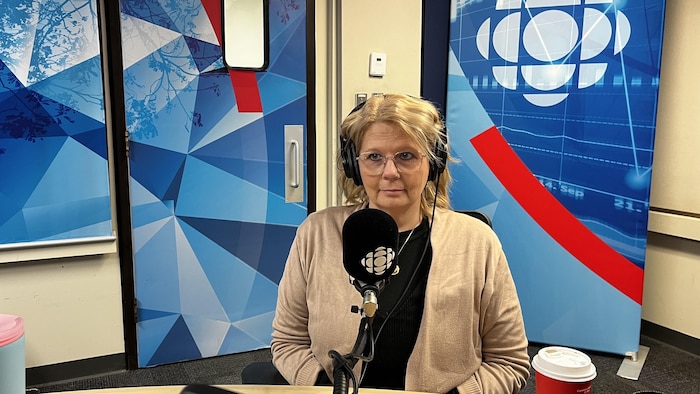Une femme assise devant un micro dans un studio de radio.