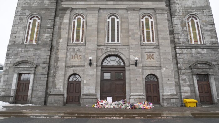 Des fleurs et des peluches sur le parvis de l'église.