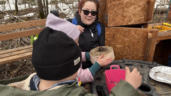 Des enfants jouent avec des morceaux de bouleau avec leur éducatrice.