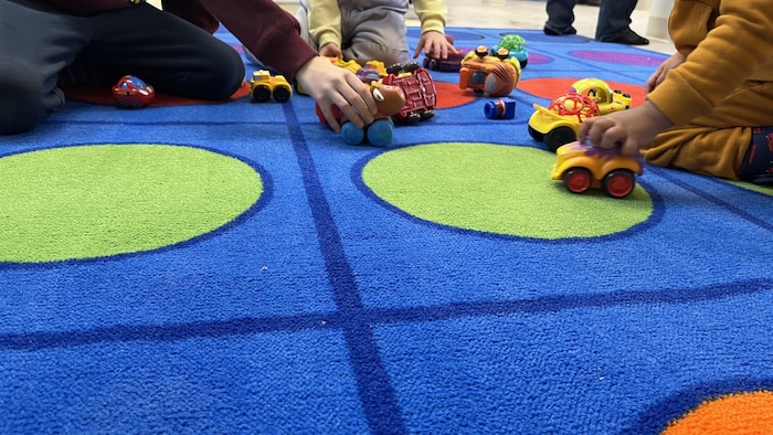 Des enfants jouent avec des petites voitures.