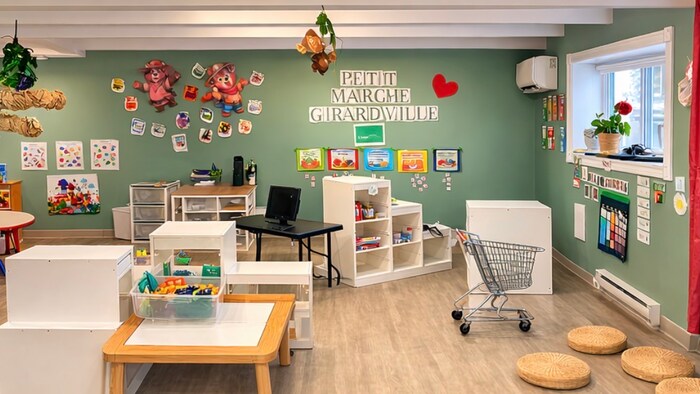 Pièce de garderie où des petits meubles et des jouets sont visibles. Les murs sont ornés de décorations colorées.