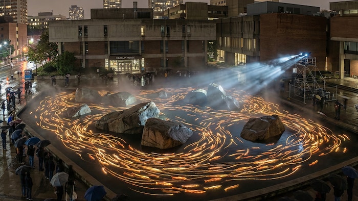 L'œuvre prend la forme d'un impressionnant banc de saumons fantômes bioluminescents et lumineux généré par un algorithme de mouvement de foule. 