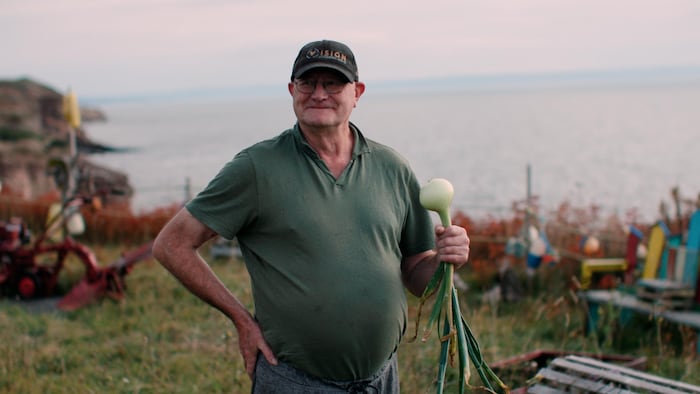 Un homme avec un oignon dans la main près de l'eau.