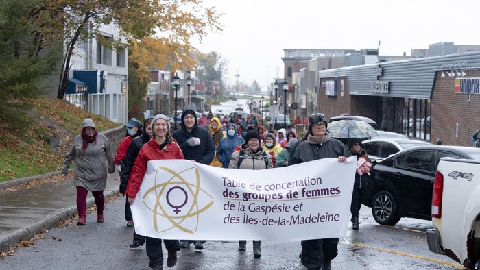 Les participants marchent sous la pluie en tenant une banderole.