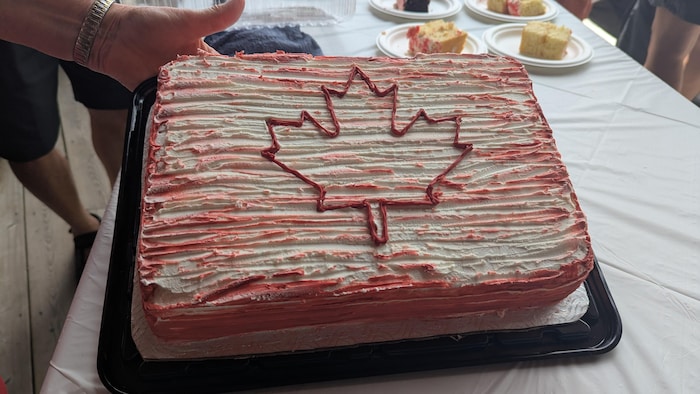 A cake with a red maple leaf is presented on a table.